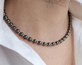May include: A black beaded necklace with gold accents. The beads are round and evenly spaced.