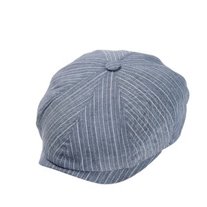 Può includere: Un cappello da newsboy a righe blu e bianche con una corona arrotondata e un visiera corta.
