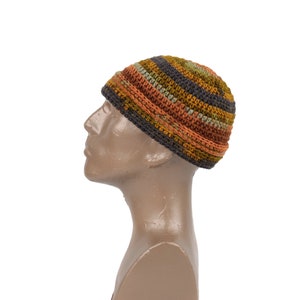 May include: A brown, orange and green striped crocheted beanie hat on a mannequin head.