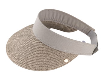 May include: A beige sun visor with a woven brim and a light gray band. The visor has a curved design and a small gold-colored emblem on the side. The band is made of a soft material and is adjustable.