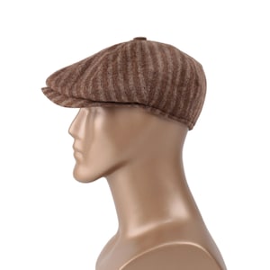 Könnte beinhalten: Eine braune und beige gestreifte Woll-Newsboy-Mütze mit flachem Oberteil und gebogenem Schirm.