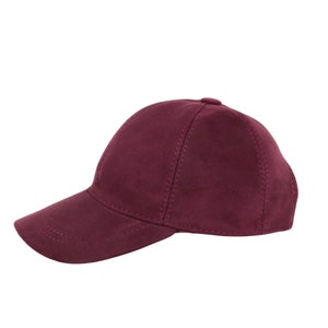 May include: A burgundy suede baseball cap with a curved brim.