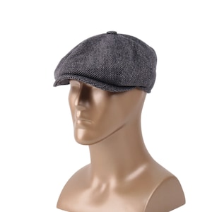 Könnte beinhalten: Eine graue Tweed-Newsboy-Mütze mit abgerundeter Krone und kurzem Schirm.