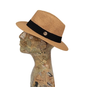 May include: A tan fedora hat with a black band and a gold button. The hat is made of straw and has a slightly curved brim.