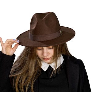 Może przedstawiać: Brązowy kapelusz fedora z brązową wstążką i małym złotym guzikiem z boku.