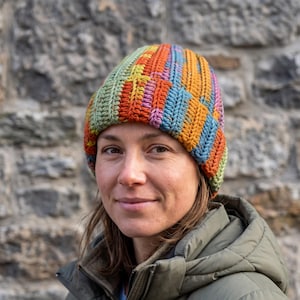 May include: A hand-crocheted beanie featuring a vibrant, multi-colored vertical striped pattern in shades of orange, green, blue, yellow, and purple. The hat is constructed with a textured, ribbed stitch design that provides a thick, warm appearance.