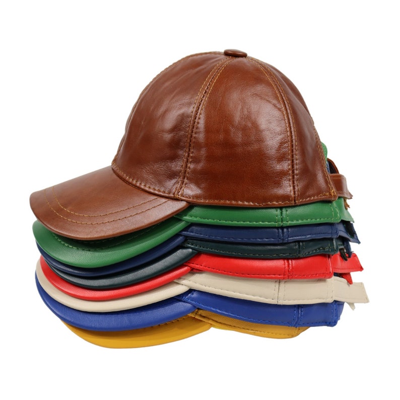 May include: A stack of eight baseball caps in various colors, including brown, green, blue, red, beige, and yellow. The caps are made of leather and have a classic baseball cap design.