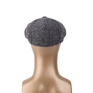 May include: A gray and black herringbone patterned newsboy cap.