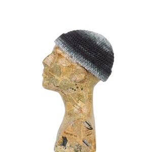 Peut inclure: Un bonnet en crochet noir et gris avec un effet dégradé. Le bonnet est sur une tête de mannequin.