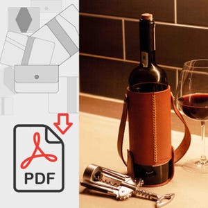 May include: A brown leather wine bottle holder with a stitched design and a metal bottle opener. The bottle holder has two straps that can be used to carry the bottle. The bottle holder is on a table with a wine glass and a bottle of wine.