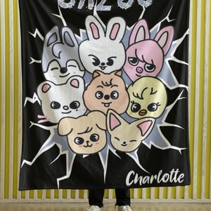 May include: Black fleece blanket with a white graphic of cartoon animals and the text "SKZOO Charlotte".