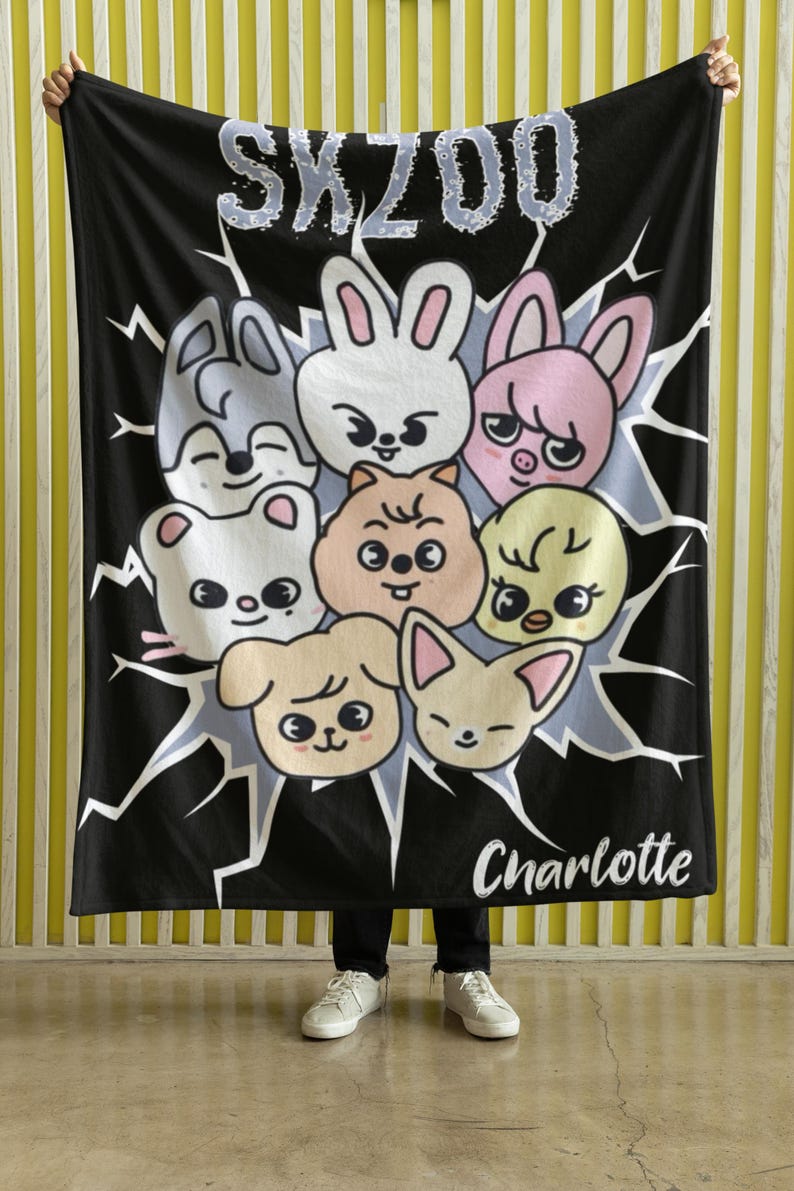 May include: Black fleece blanket with a white graphic of cartoon animals and the text "SKZOO Charlotte".