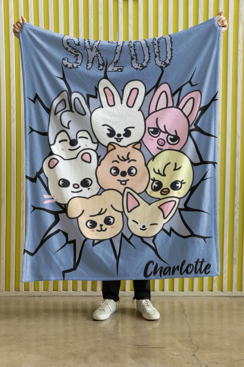 May include: A blue fleece blanket with a cartoon design featuring a group of animals with the text "SKZOO" and "Charlotte" printed on it.