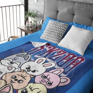 Puede incluir: Una manta de forro polar azul con un dise&ntilde;o de dibujos animados de cinco animales. Los animales son un conejo, un cerdo, un gato, un zorro y un pollito. La manta tiene la palabra "Kawaii" escrita en ella en una fuente estilizada.