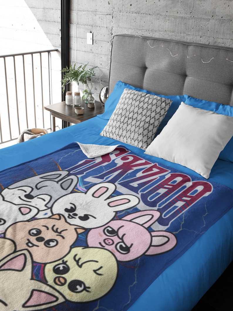 Puede incluir: Una manta de forro polar azul con un dise&ntilde;o de dibujos animados de cinco animales. Los animales son un conejo, un cerdo, un gato, un zorro y un pollito. La manta tiene la palabra "Kawaii" escrita en ella en una fuente estilizada.