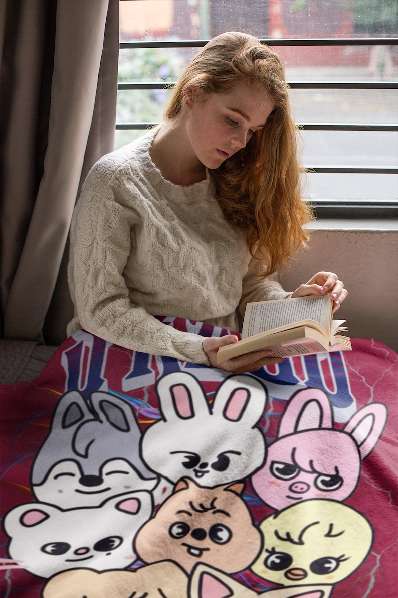 Puede incluir: Una manta roja, blanca y azul con un dise&ntilde;o de dibujos animados de varios animales, incluyendo un conejo, un gato, un perro, un cerdo y un pollo. Todos los animales sonr&iacute;en y tienen ojos grandes.