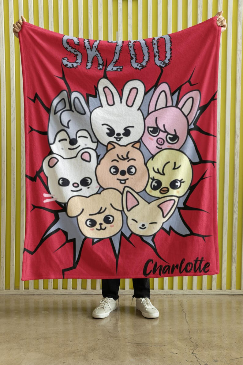 May include: Red fleece blanket with a cartoon design featuring a group of animals with the text "SKZOO" and "Charlotte" printed on it.
