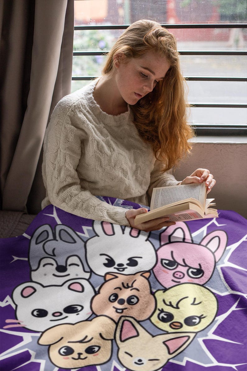 May include: A purple fleece blanket with a cartoon design featuring various animals with smiling faces. The animals include a rabbit, a pig, a bear, a bird, and a dog. The blanket is soft and cozy, perfect for snuggling up on the couch.