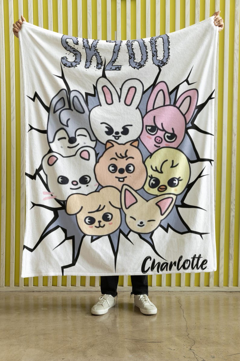 May include: White fleece blanket with a cartoon design featuring a group of animals with the text "SKZOO" and "Charlotte" printed on it.