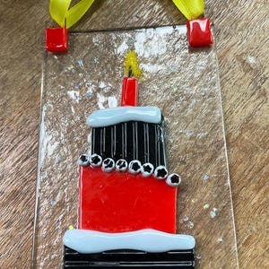 May include: A white ceramic mug with a black handle and the text "But First, Coffee" in a black, bold font. The mug is sitting on a wooden surface. The mug is approximately 4 inches tall.