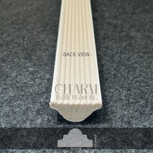 May include: Back view of a white, fluted, decorative molding with a rounded edge. The molding is 4 inches wide and 2.5 inches tall. The text "CHARM Wallcreations" is printed on the molding.