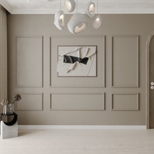 May include: A beige wall with white trim and a framed abstract art print with a black stripe. The wall is decorated with a modern light fixture with white, organic-shaped shades.