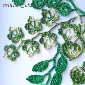 May include: A collection of crocheted green and white leaves and flowers. The leaves are in various shades of green, and the flowers are a combination of green and white.