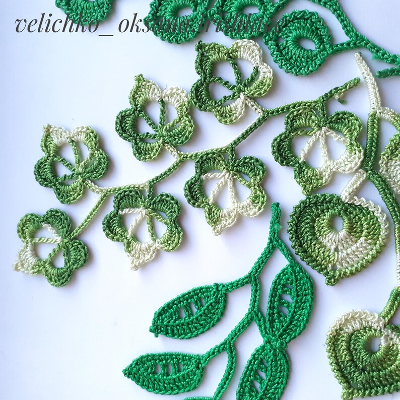 May include: A collection of crocheted green and white leaves and flowers. The leaves are in various shades of green, and the flowers are a combination of green and white.