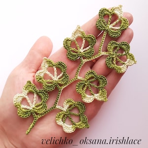May include: A crocheted green and white leaf design with a delicate, intricate pattern. The design is made with a combination of green and white yarn, creating a beautiful contrast.