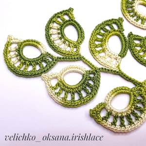 May include: A close-up of a crocheted green and white leaf design. The leaves are connected by a stem and have a delicate, lacy appearance.