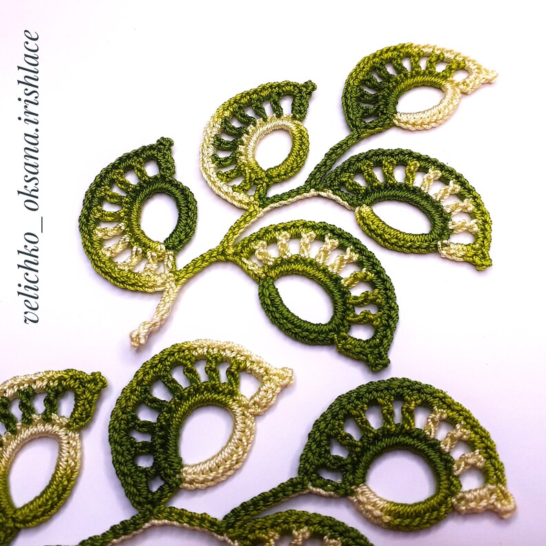 May include: Green and cream crocheted leaves with a delicate, intricate design. The leaves are connected to form a branch-like shape.