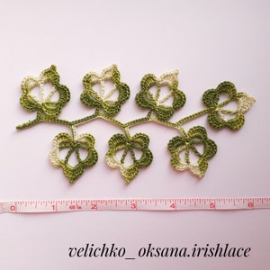 May include: A crocheted green and white leaf garland with a ruler for scale. The garland is approximately 6 inches long.