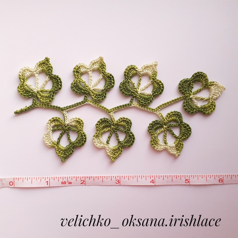 May include: A crocheted green and white leaf garland with a ruler for scale. The garland is approximately 6 inches long.