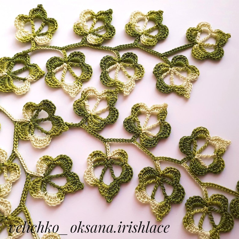 May include: A delicate crocheted lace design featuring a vine with green and cream leaves. The leaves are intricately detailed and create a beautiful pattern.