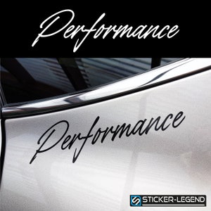 Op de afbeelding: Zwarte vinyl sticker met het woord "Performance" geschreven in een cursief schrift. De sticker is aangebracht op de zijkant van een zilveren auto.