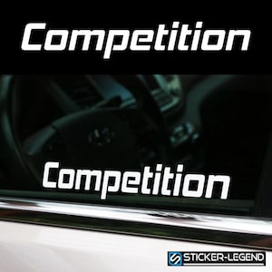 Könnte beinhalten: Weißer Vinyl-Aufkleber mit dem Wort "Competition" in fetten, weißen Buchstaben auf schwarzem Hintergrund. Der Aufkleber ist auf die Heckscheibe eines Autos geklebt.