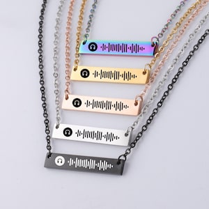 May include: Five silver necklaces with a bar pendant featuring a headphone icon and a Spotify barcode. The necklaces are in different colours: black, silver, gold, rose gold, and rainbow.