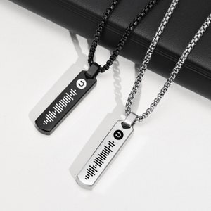 May include: Two silver necklaces with black chain links. Each necklace has a rectangular pendant with a music note symbol and a barcode-like design. One pendant is black and the other is silver.