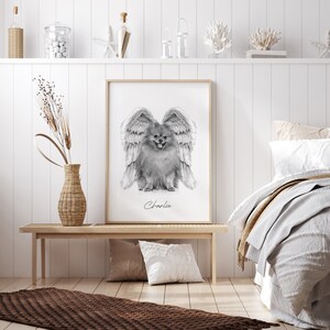 May include: Black and white drawing of a dog with angel wings. The dog is a Pomeranian and is sitting with its tongue out. The drawing is framed and the name "Charlie" is written below the dog.