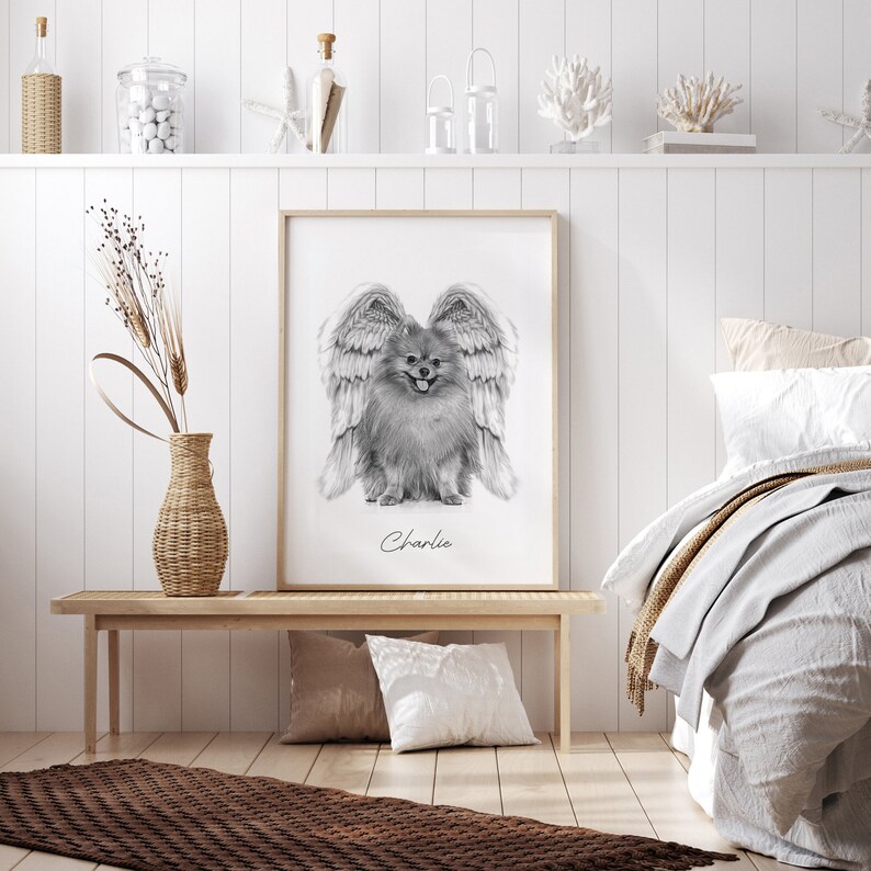 May include: Black and white drawing of a dog with angel wings. The dog is a Pomeranian and is sitting with its tongue out. The drawing is framed and the name "Charlie" is written below the dog.