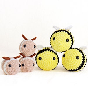 Könnte beinhalten: Sechs gehäkelte Bienen- und Schmetterlingstiere. Die Bienen sind gelb mit schwarzen Streifen und weißen Flügeln. Die Schmetterlinge sind braun mit schwarzen Augen.