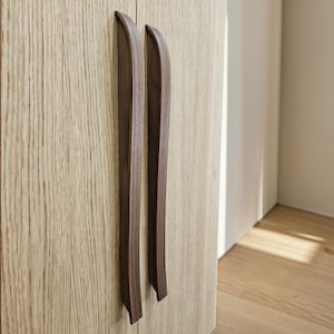 Peut inclure: Une tasse en céramique blanche avec une anse noire et le texte "But First, Coffee" en gras noir. La tasse contient probablement 325 ml et est posée sur une surface blanche.