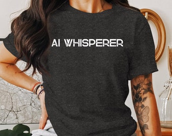 May include: A dark gray t-shirt with the text "AI WHISPERER" printed in white on the front.