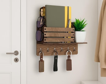 May include: A wooden wall-mounted organizer with a shelf, key hooks, and storage compartments. It holds a small potted plant, notebooks, and sunglasses. Keychains hang from the hooks. The organizer is made of dark brown wood.