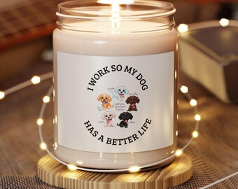 Puede incluir: Una vela encendida en un tarro de cristal transparente con una etiqueta blanca. La etiqueta dice "I WORK SO MY DOG HAS A BETTER LIFE" con ilustraciones de varias razas de perros. La vela está sobre un posavasos redondo de madera.