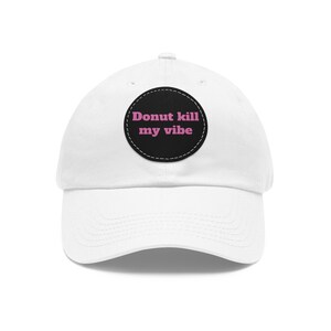 May include: White baseball cap with a black circle patch that says "Donut kill my vibe" in pink letters.