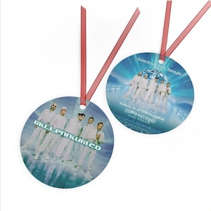 Peut inclure: Deux décorations de Noël rondes avec des rubans rouges. L'une affiche le texte "Millennium 20" et un groupe de personnes en tenues blanches. L'autre dit "Backstreet Boys" et "Sphere Las Vegas".