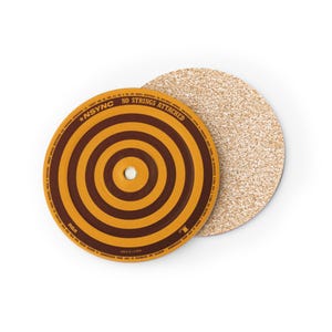 Op de afbeelding: Twee ronde onderzetters. Eén heeft een bruin en geel bullseye-ontwerp met de tekst "*NSYNC NO STRINGS ATTACHED". De andere is gemaakt van kurk. Deze onderzetters zijn ontworpen om oppervlakken te beschermen tegen condensatie van drankjes.