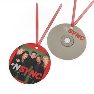May include: Two round Christmas ornaments with red ribbons. One features a photo of *NSYNC with the text "NSYNC Home for Christmas". The other is a CD with the band's name in red.