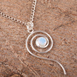 Könnte beinhalten: Eine silberne Halskette mit einem spiralförmigen Anhänger mit einem weißen Opal-Edelstein.